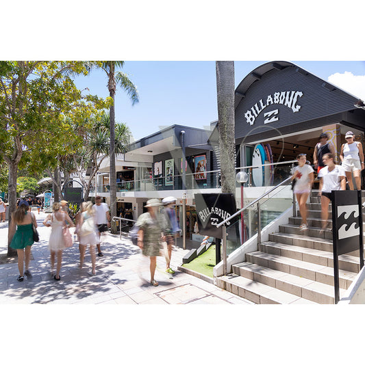 Hastings Street Image 5442 by AWP Image Library captures a bustling shopping area with a Billabong store, people walking and browsing, palm trees lining the sunny sidewalk, and a lively atmosphere.