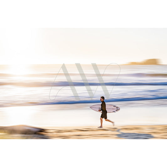 The Mudjimba Beach Surfer Image 5504 from AWP Image Library captures a surfer running on the sand, holding a surfboard as the ocean waves blend softly in the bright sunshine.