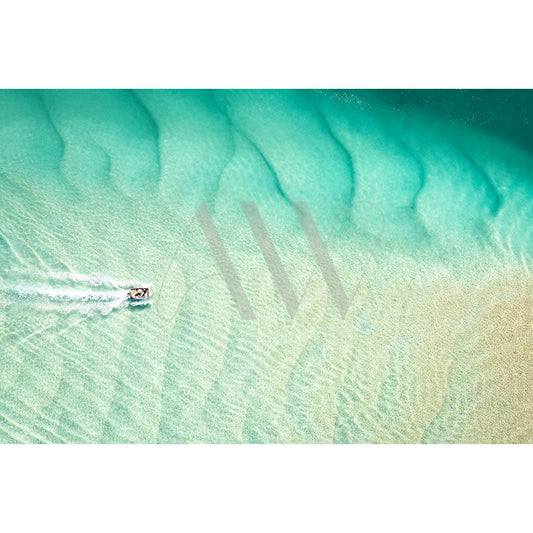 The AWP Image Library presents Noosa Drone Image 0333, capturing a small boat racing over clear turquoise waters. The visible seabed displays sand patterns through the shallow water, creating a textured, wavy effect beneath the white wake.