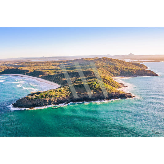 The Noosa Drone Image 0496 from AWP Image Library captures a coastal landscape with a lush green peninsula, turquoise waters, sandy beaches, and a clear horizon beneath a blue sky.