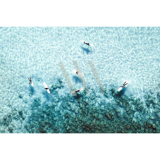 Noosa Drone Image 0959 by AWP Image Library captures an aerial view of six surfers on their boards over crystal-clear turquoise water near a reef, with a shimmering ocean surface creating a tranquil and picturesque scene.