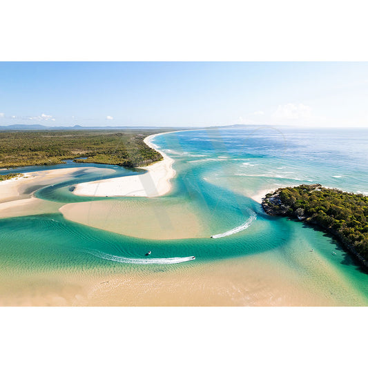 The Noosa Sound Image 0295 from AWP Image Library captures an aerial view of a coastal landscape where a winding river meets the ocean, bordered by white sandy beaches and lush green vegetation under a clear blue sky.